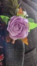 Handmade light orchid satin rose boutonniere pinned on dark gray suit lapel with green leaves