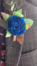Handmade royal blue satin rose boutonniere with green leaves pinned on gray suit lapel